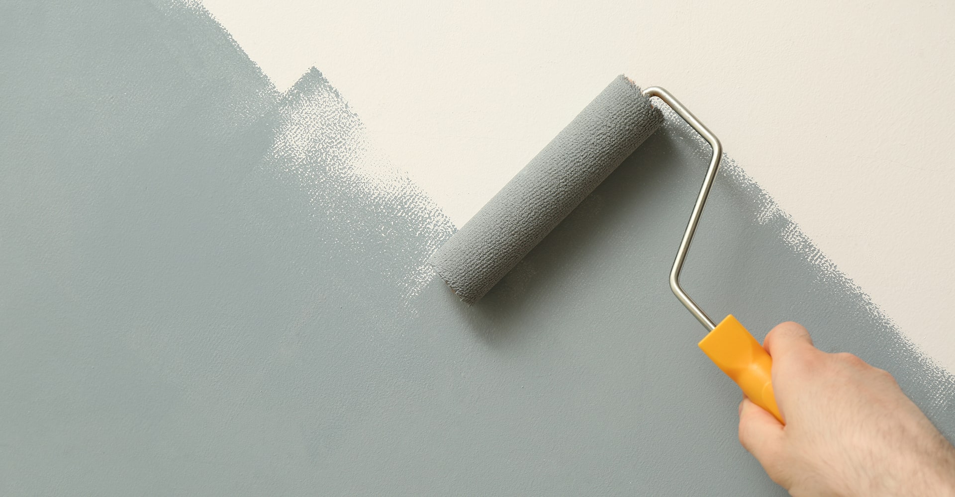 Gros plan sur la main d'un conducteur portant une montre-bracelet argentée, tenant le volant au crépuscule avec des lumières de ville floues en arrière-plan.
