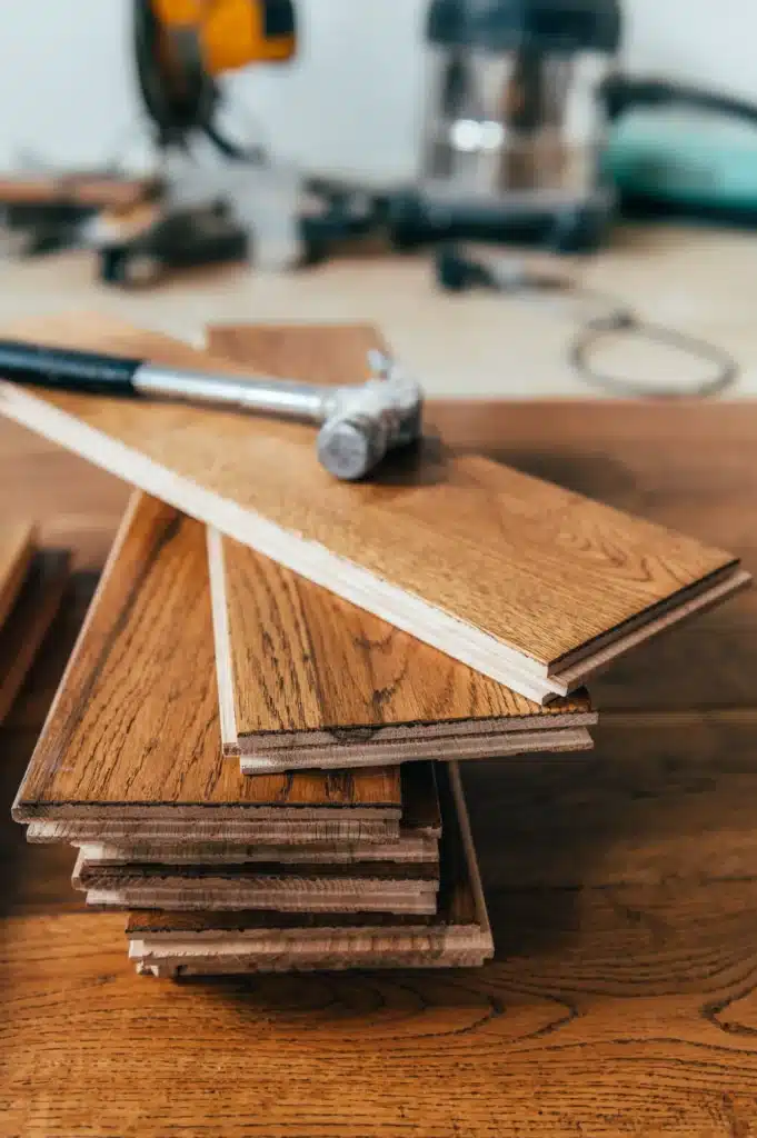 Parquet Bois : Installation facile de planches d'ingénierie. Installation de parquet. Pile de planches de bois d'ingénierie (chêne) avec rainures et languettes, marteau posé dessus.